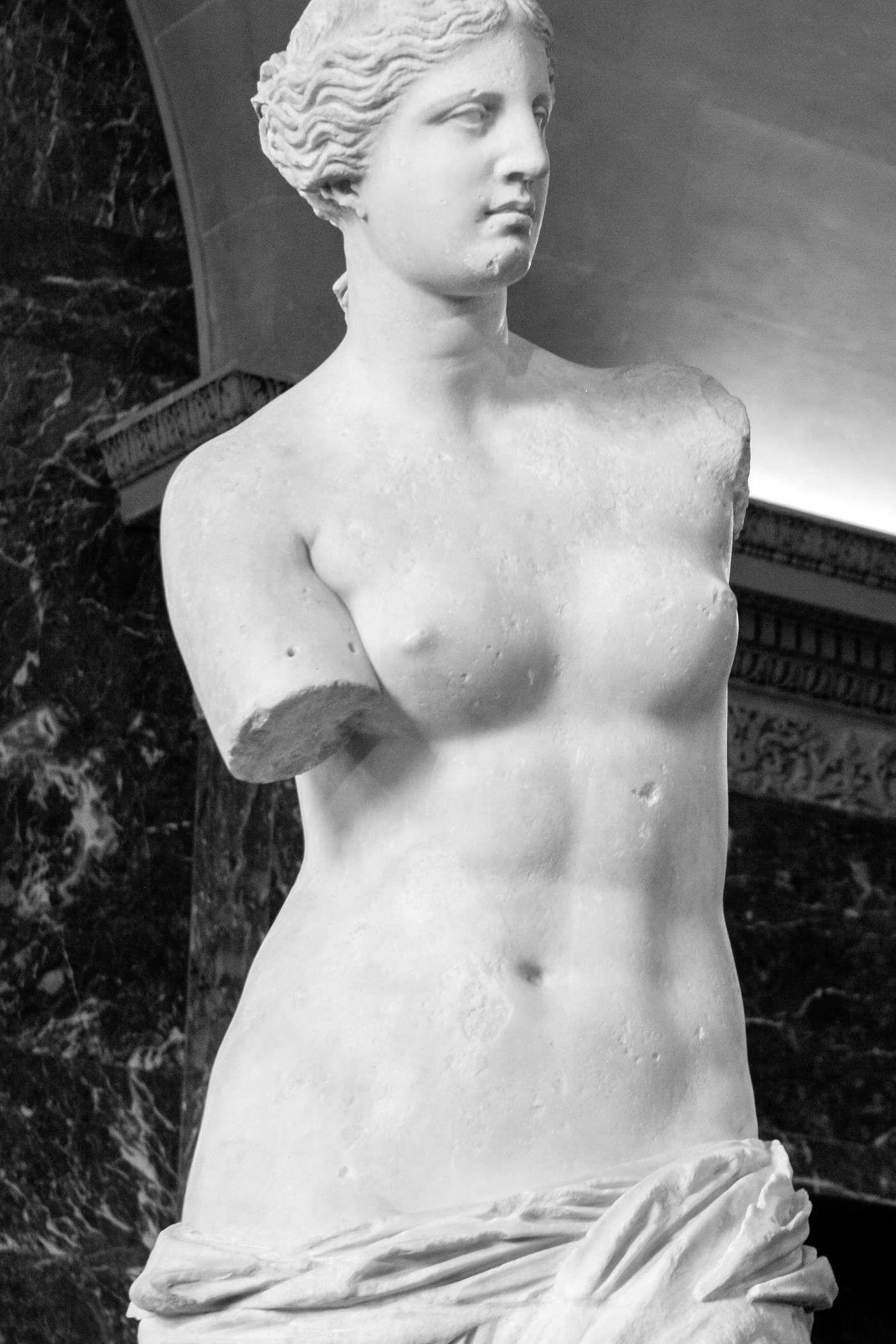 Grayscale photo of the famous Venus de Milo statue in the Louvre Museum, Paris.