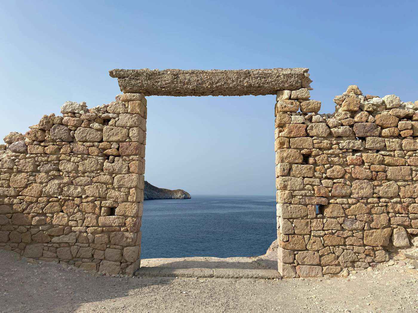 9323915 Historic stone structure framing a breathtaking Aegean Sea view on Milos, Greece.