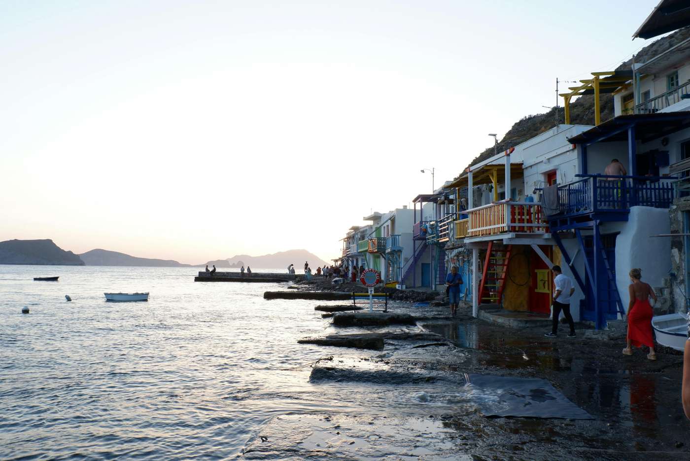 13451083 Beautiful seaside view of Klima village at sunset, showcasing colorful houses and serene waters.