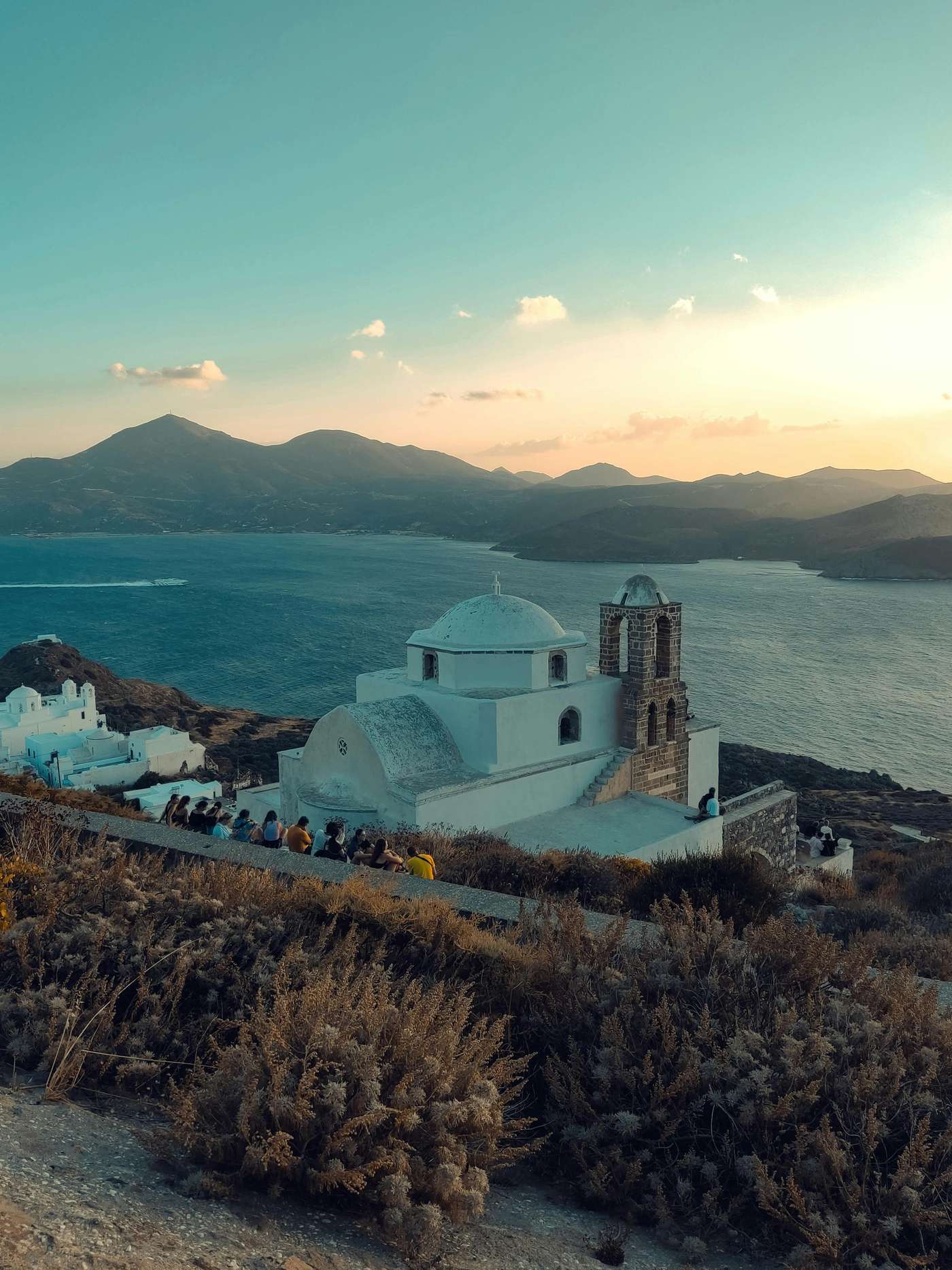 Experience the breathtaking view of the Venetian Castle in Milos, Greece, overlooking the sea at sunset.