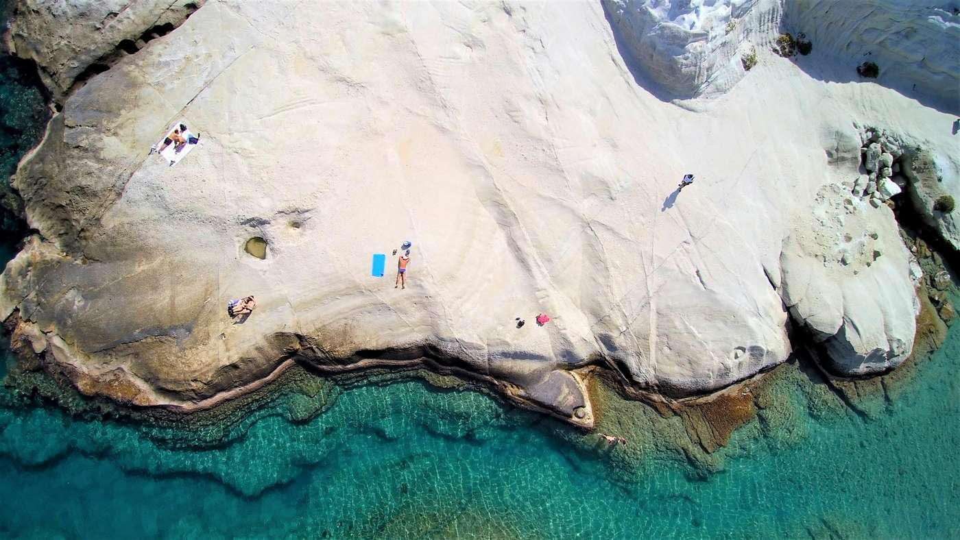 6359754 A breathtaking aerial view of Sarakiniko Beach in Milos, Greece, showcasing white rock formations and azure waters.